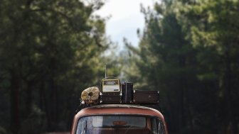 roof of car on wooded road with luggage on top 