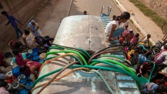 People in New Delhi, India, using hoses to fill jerry cans with drinking water