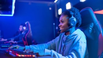 Portrait Streamer African young woman professional gamer playing online games computer, neon color.