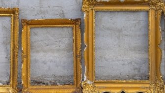 Three golden frames leaning against a wall