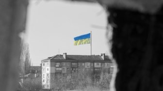 View through the window of the ruined house on the flag of Ukraine in the blue sky. Russia's aggression against Ukraine. The concept of peace after the war.f