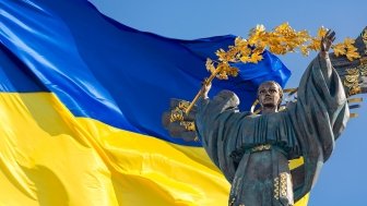 Monument of Independence of Ukraine in front of the Ukrainian flag. The monument is located in the center of Kyiv on Independence Square.