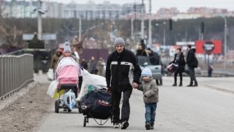 Group with children carrying items down a road