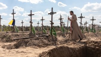 A priest overseas the burial of the remains of 13 unidentified and two identified people who were killed in the Bucha district during the Russian occupation