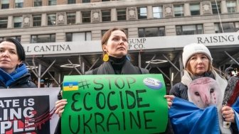 Woman holding sign with "Stop Ecocide Ukraine" written on it 