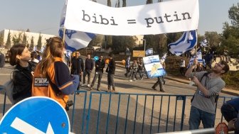 Protesters carrying sign comparing Netanyahu and Putin