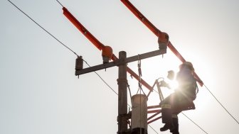 Lineman electrician engineer working climbing a pole to repair and maintain a power line and a transformer