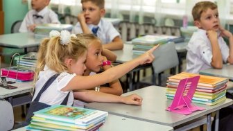 Odessa, Ukraine - September 1, 2015: elementary school students at their desks with textbooks on the first day of the school year. Feast Day of Knowledge. Beginning of a new academic year.