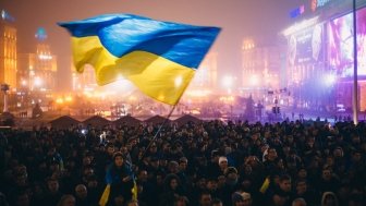 A Ukrainian flag is waved over a busy square. 