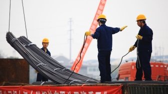 China's eastern city of Jiujiang, workers in the steel building materials market hoisting steel