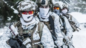 Action in cold conditions. Squad of soldiers with weapons in forest somewhere above the Arctic Circle