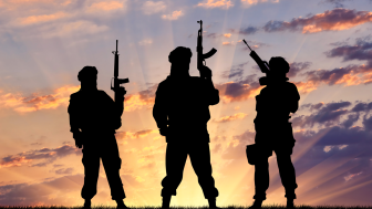 Concept of a terrorist. Silhouette terrorists with rifle at sunset