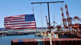 Newark, NJ / USA - March 28 2020: US flag on the mast of cargo ship berthed in the container terminal in Newark.