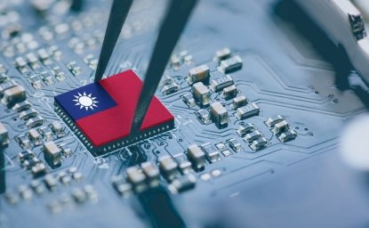 A circuit board with a pair of tweezers placing a part on the board, the part has the map of Taiwan on it.