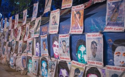 Posters of missing students line a wall.