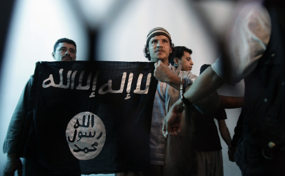 n this April 23, 2013 file photo, a suspected Yemeni al-Qaida militant, center, holds a banner as he stands behind bars during a court hearing in state security court in Sanaa, Yemen