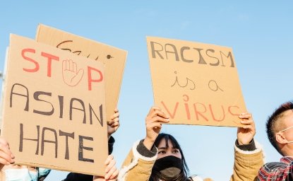 Signs of protestors, "Stop Asian Hate" and "Racism is a Virus"