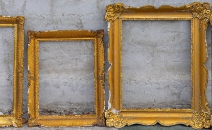 Three golden frames leaning against a wall