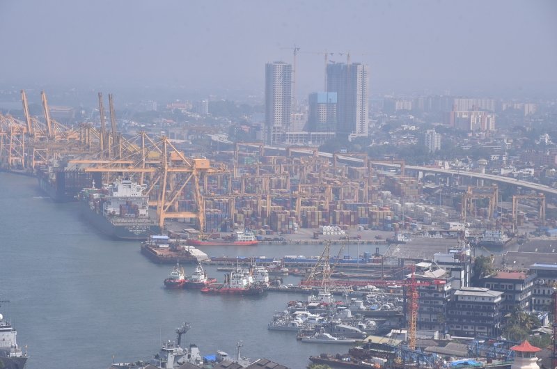 An aerial view of a port with cranes, ships, and skyscrapers.