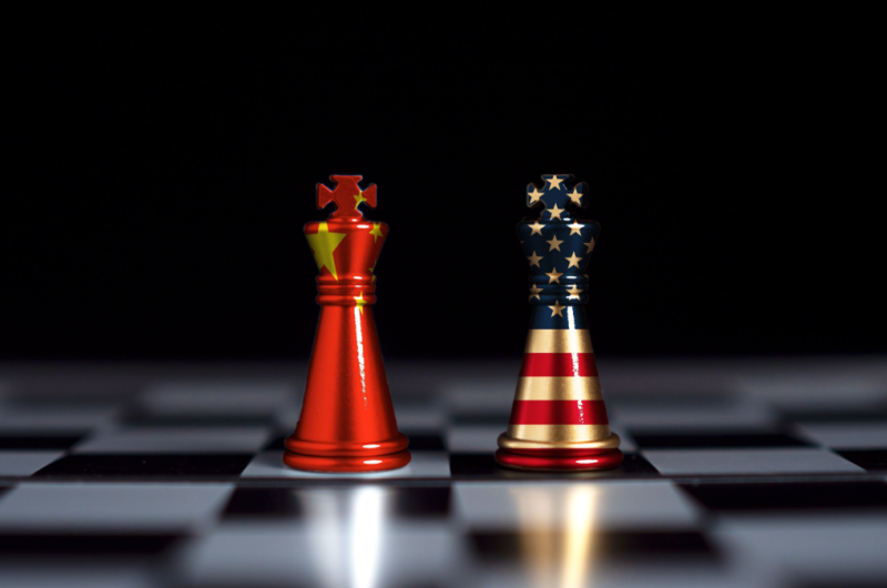 Chess pieces stand text to each other wrapped in the US and Chinese flags