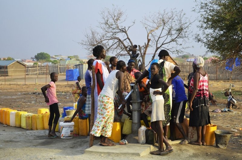 Juba, South Sudan, February 2017. People with yellow jerrycans waiting for water at a borehole site. Salesian camp for internally displaced persons (IDPs). Captured during civil war.