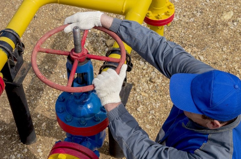 Image of a worker opening, closing the shut-off valves at the gas pumping station. Part of the photo is blurry.