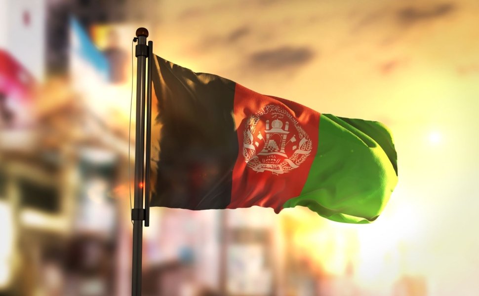 The flag of Afghanistan in front of a bright, blurry background.