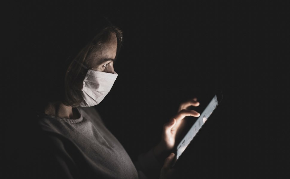 Woman with face mask staring at cell phone