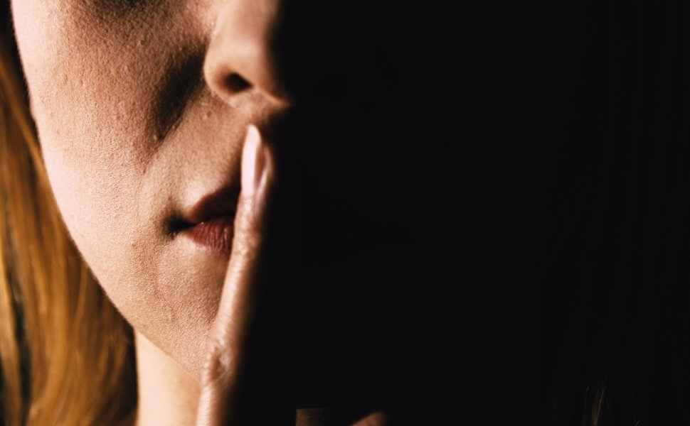 Seriouse woman placing her finger on lips - keep silence or secret. Mouth close up