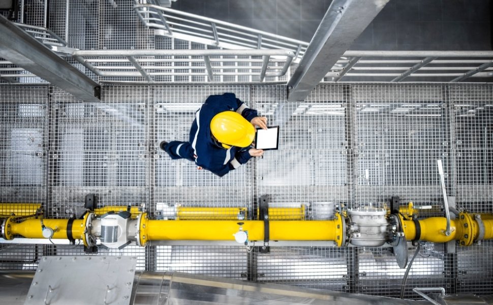 Man in a hardhat walking next to a pipeline