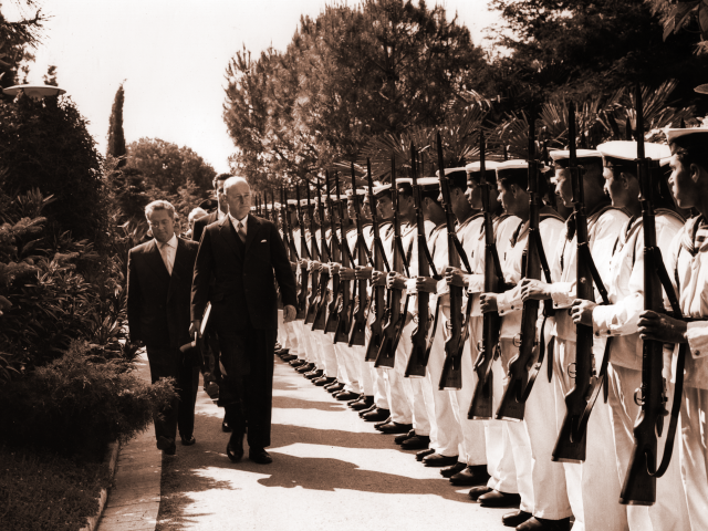 George F. Kennan stands before a line of soldiers