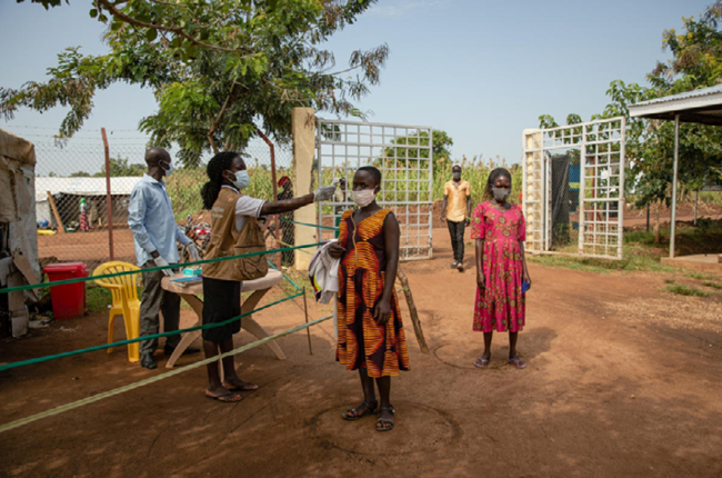 A South Sudanese refugee has her temperature checked before entering a health centre in Uganda’s Bidibidi refugee settlement. © UNHCR/Esther Ruth Mbabazi