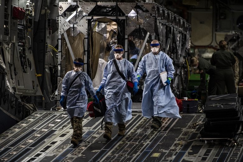 Three U.S. Air Force medical Airmen exit a C-17 Globemaster III following the first-ever operational use of the Transport Isolation System at Ramstein Air Base, Germany, April 10, 2020. The TIS is an infectious disease containment unit designed to minimize contamination risk to aircrew and medical attendants, while allowing in-flight medical care for patients afflicted by a disease—in this case, COVID-19.