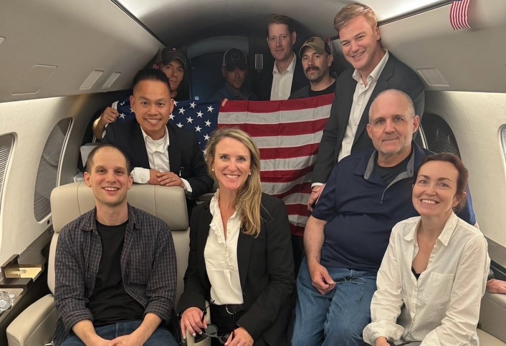 Americans detained in Russia pose on a plane on their way home