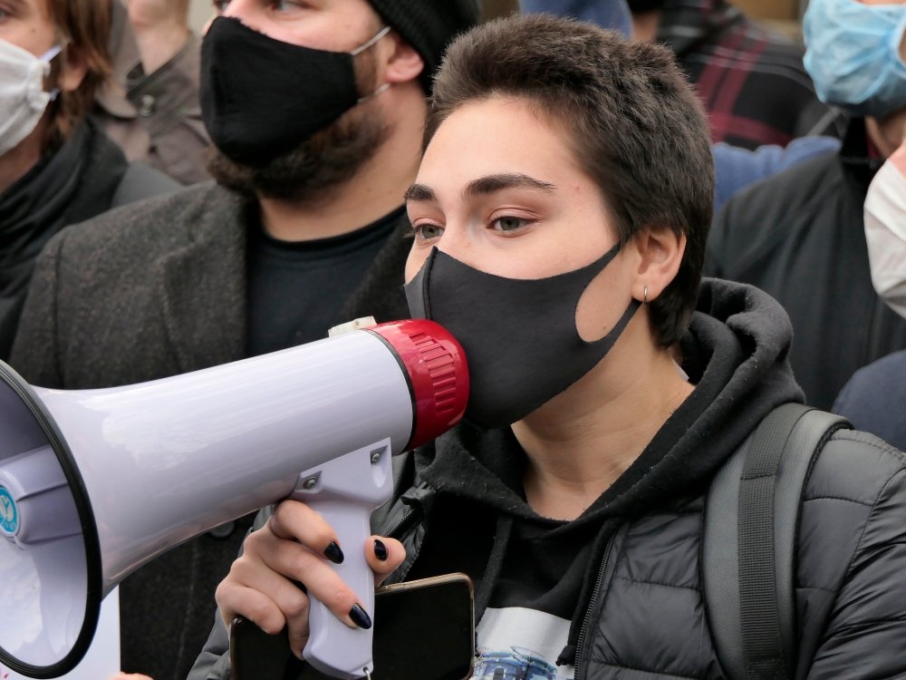 Kiev/Ukraine - October 26, 2020: young dark haired woman with medical mask on face shout out slogans to loudspeaker at street protest rally against abortion ban in Poland near Polish embassy in Kyiv