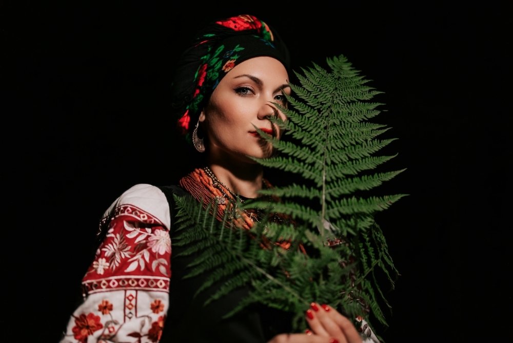 A woman in traditional Ukrainian handkerchief and vyshyvanka holding a leaf.