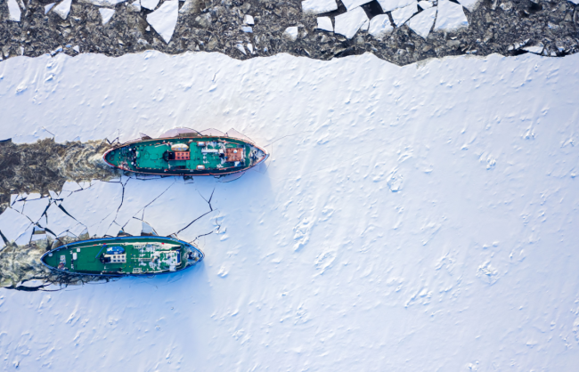 Ice breakers crush through the ice in an aerial shot