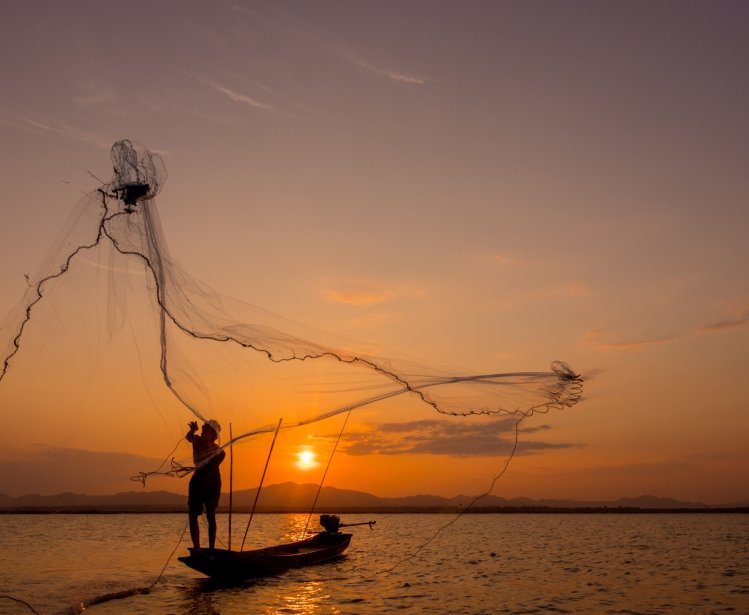 Silhouette of fisherman throwing net on the lake, Shutterstock