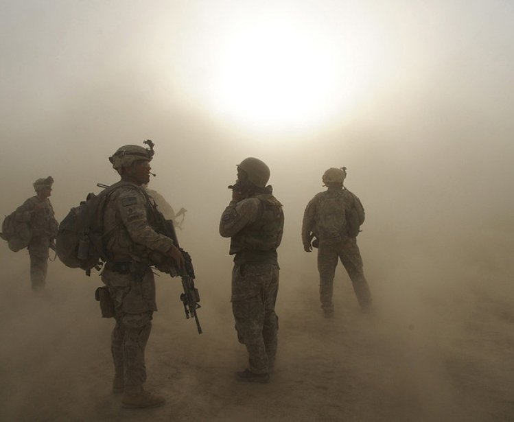 Soldiers watche as CH-47 helicopters circle above during a dust storm at Forward Operating Base Kushamond 