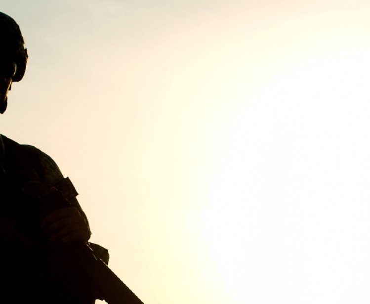 A soldier is silhouetted against a sunset