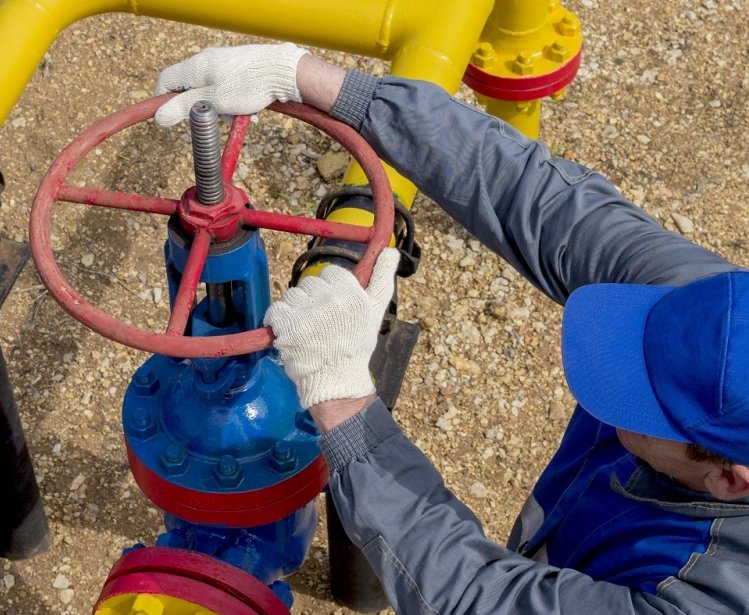 Image of a worker opening, closing the shut-off valves at the gas pumping station. Part of the photo is blurry.