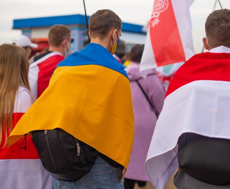 A group of protesters holding Ukrainian and Belorusian white and red flag