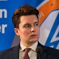 A photo of Lucas Myers speaking at a conference with the Wilson Center logo in the background.