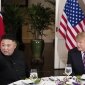 Kim Jong Un sits at a dinner table next to Donald J. Trump