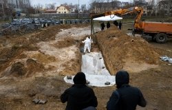 Forensic experts are working to dig up bodies from a clandestine grave found behind a church in the town of Bucha.