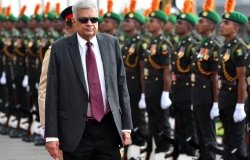 A picture of President Ranil Wickremesinghe in front of a line of army members.