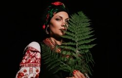 A woman in traditional Ukrainian handkerchief and vyshyvanka holding a leaf.