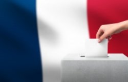 Hand putting a vote into a ballot box in front of the French flag