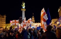 A crowd of protesters in front of the monument in Liberty Square in Tbilisi wave Georgian flags and EU flags. 